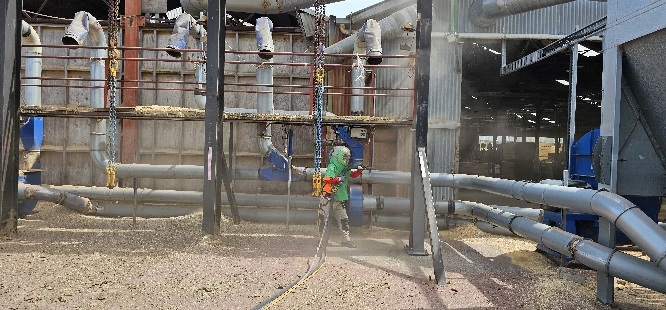 Steel blasting on industrial pipework.